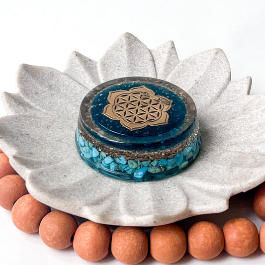 An image of a handmade cylinder orgonite with turquoise stones ,6.5cm  diameter by 2.5cm in height